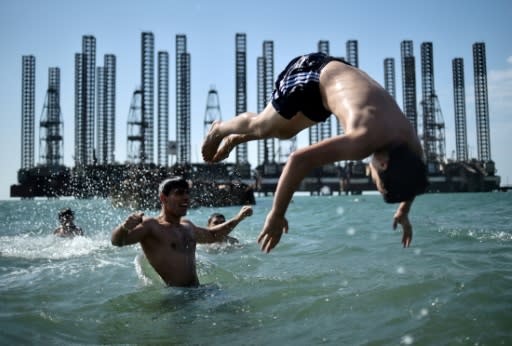 Swimmers in the Caspian Sea near oil rigs in the Azerbaijani capital Baku