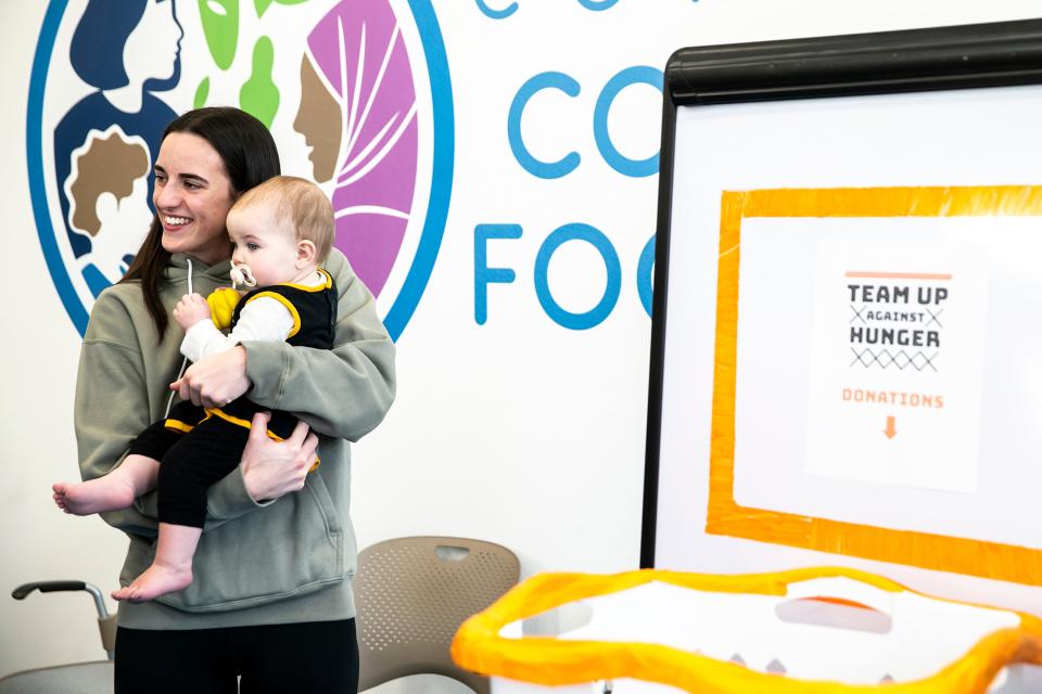Iowa women's basketball guard Caitlin Clark holds a 1-year-old baby Ivy of Coralville while posing for a photo with fans who donated to the Coralville Community Food Pantry, Friday, April 21 at 804 13th Avenue. Fans who donated at least $22 or brought health items could meet with Clark as part of the Team Up Against Hunger campaign. The food pantry opened its new location earlier this month.