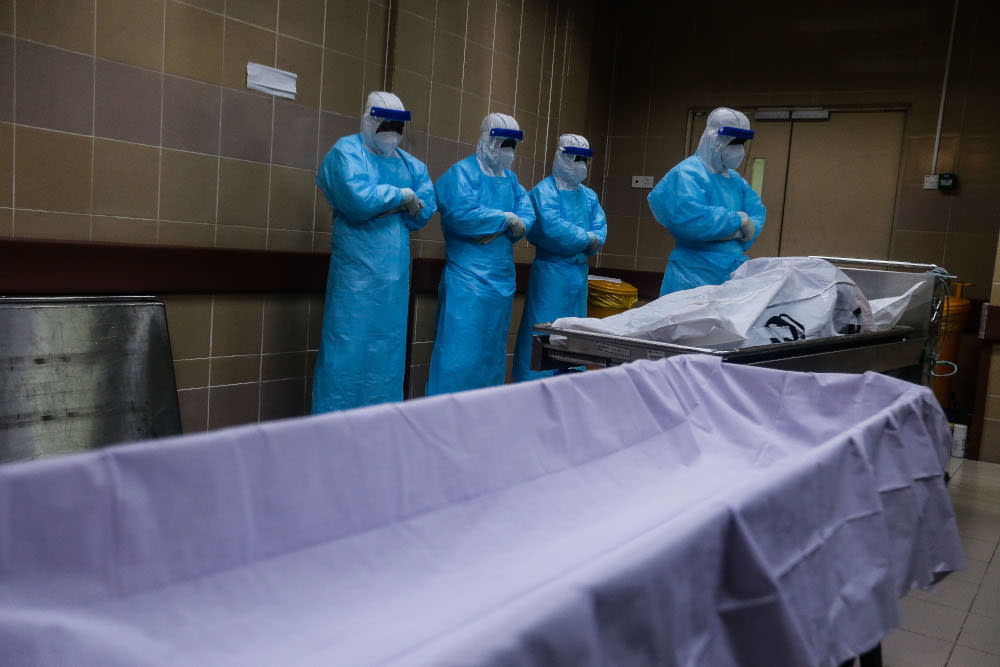 Forensic personnel conduct prayers for a recently deceased Covid-19 patient as they prepare the body for burial at the Penang General Hospital, August 24, 2021. — Picture by Sayuti Zainudin