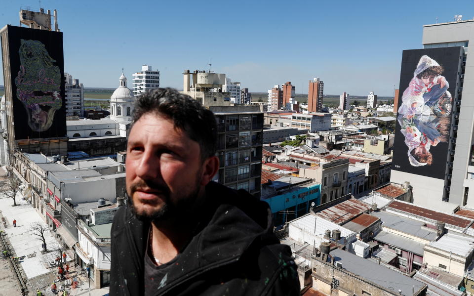 Argentine artist Martin Ron poses for a portrait in front of his murals, about the historical drought that has lowered the level of the country's most important river, the Parana, in San Nicolas, Argentina September 16, 2021. Picture taken September 16, 2021. REUTERS/Agustin Marcarian