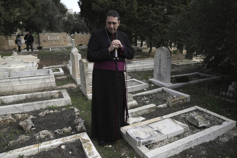 Hosam Naoum, a Palestinian Anglican bishop, pauses where vandals desecrated more than 30 graves at a historic Protestant Cemetery on Jerusalem's Mount Zion in Jerusalem, Wednesday, Jan. 4, 2023. Israel's foreign ministry called the attack an "immoral act" and "an affront to religion." Police officers were sent to investigate the profanation. (AP Photo/ Mahmoud Illean)