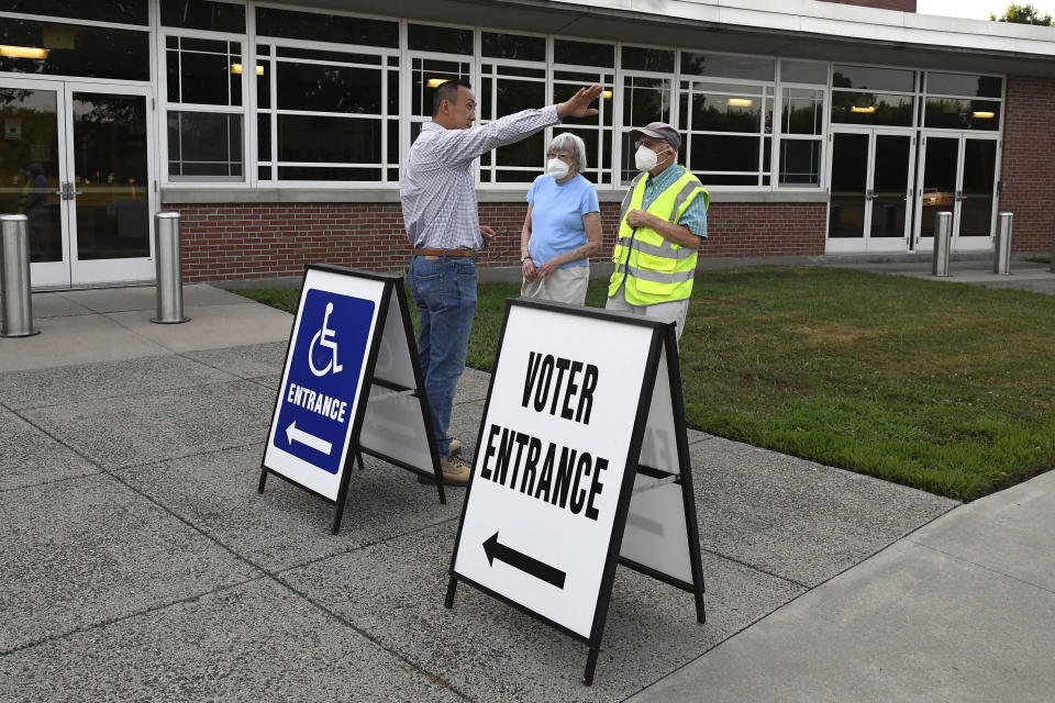 Republican First Selectman Colin Moll, left, talks with Suffield residents Richard and Connie Davis before they vote in the state's on primary election, Tuesday, Aug. 9, 2022, in Suffield, Conn. Suffield is one of several small towns in Connecticut where control was flipped from Democrats to Republicans in 2021 municipal races. Moll is volunteering as a poll worker for the day. (AP Photo/Jessica Hill)