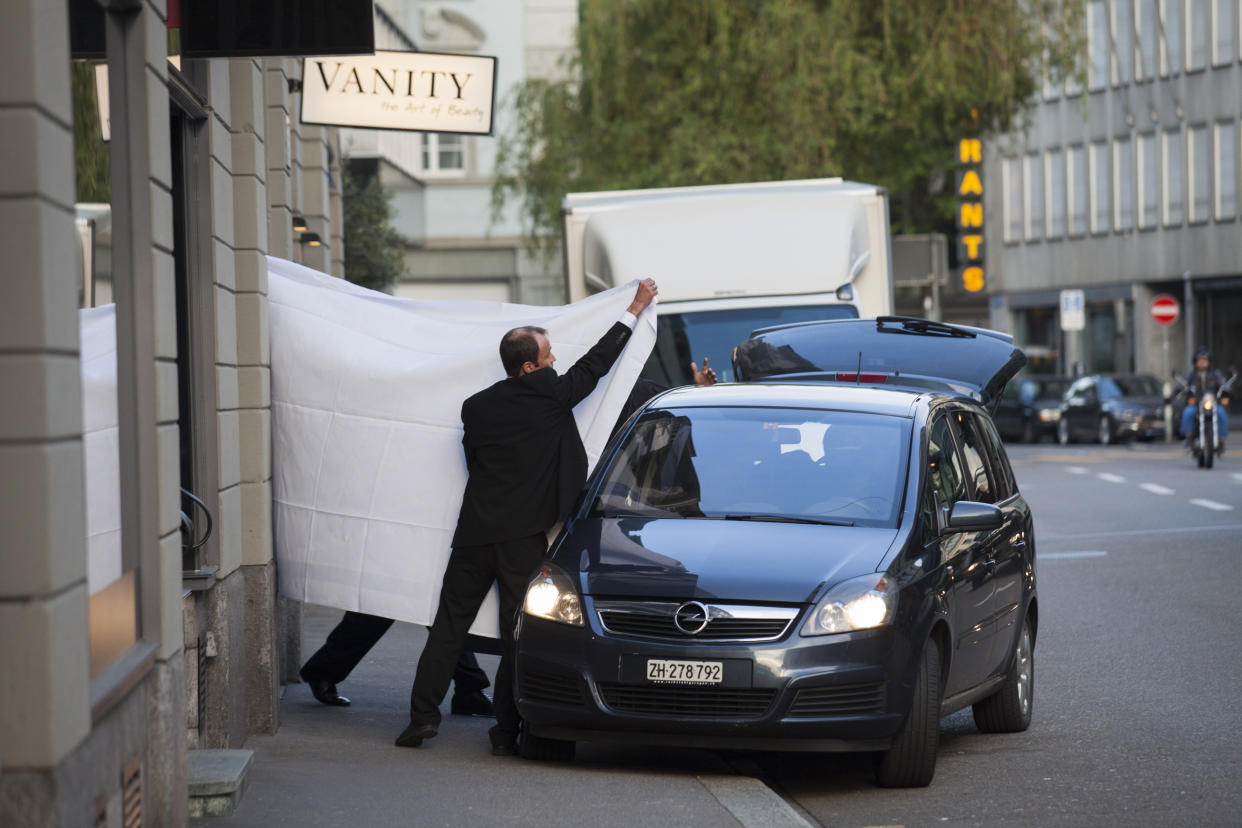 Agentes encargados de hacer cumplir la ley utilizan sábanas para proteger las identidades de los funcionarios de la FIFA, el órgano rector del fútbol mundial, arrestados por cargos de corrupción, afuera del Hotel Baur Au Lac en Zúrich, el 27 de mayo de 2015. (Pascal Mora/The New York Times)