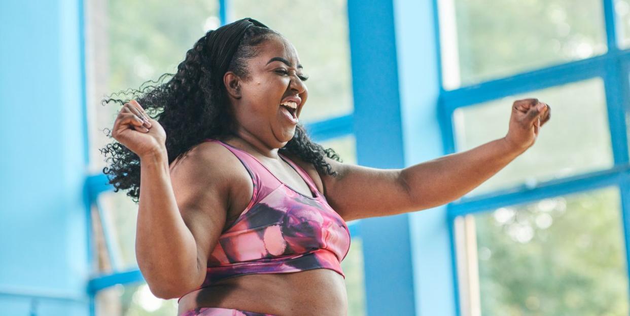 woman in colourful gym attire dancing and smiling