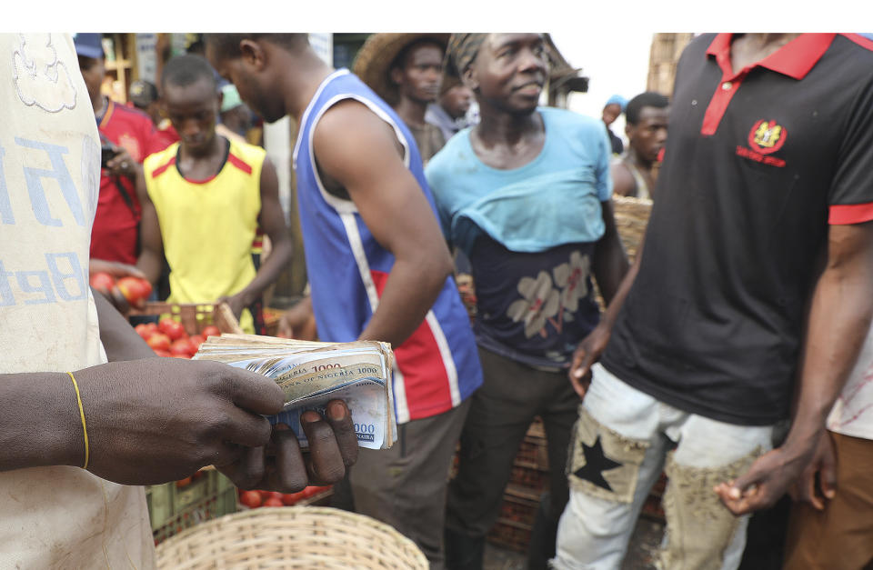 A vendor counts local currency at a Mile 12 Market in Lagos, Nigeria, Friday, Feb. 16, 2024. Nigerians are facing one of the West African nation's worst economic crises in as many years triggered by a surging inflation rate which follows monetary policies that have dipped the local currency to an all-time low against the dollar, provoking anger and protests across the country. (AP Photo/Mansur Ibrahim)