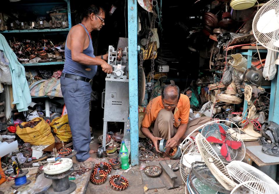 Men repair fans inside a workshop in Kolkata, India, 28 April 2022 (Reuters)