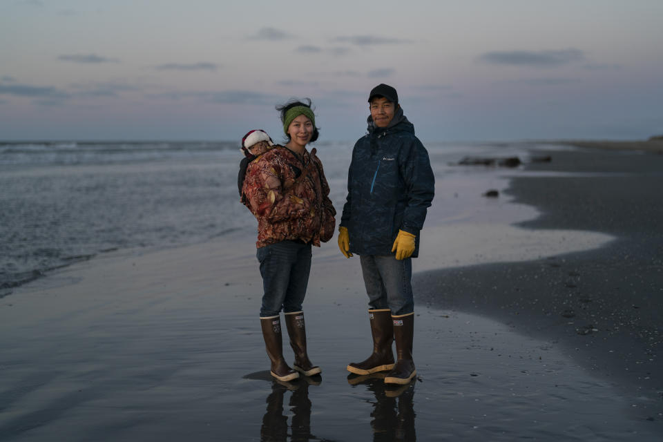 Ned Ahgupuk, 26, and girlfriend Kelsi Rock, stand for a photo with their 1-year-old son Steve Rock-Ahgupuk while strolling along the beach on the Arctic Ocean in Shishmaref, Alaska, Friday, Sept. 30, 2022. "We've been here all our lives," said Ahgupuk. He said climate change is a concern but he won't leave the island. "Everyone is like a big family caring for each other." (AP Photo/Jae C. Hong)