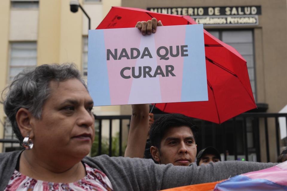 A member of the LGBTQ+ community holds up a sign with a message that reads in Spanish: "Nothing to cure", during a protest against a decree following a decision by the Ministry of Health classifying transgenders as mentally ill, in Lima, Peru, Friday, May 17, 2024. (AP Photo/Martin Mejia)