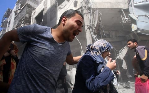 Fareed al-Mhlol leads his mother out of the house after an air strike in Idlib - Credit: AFP