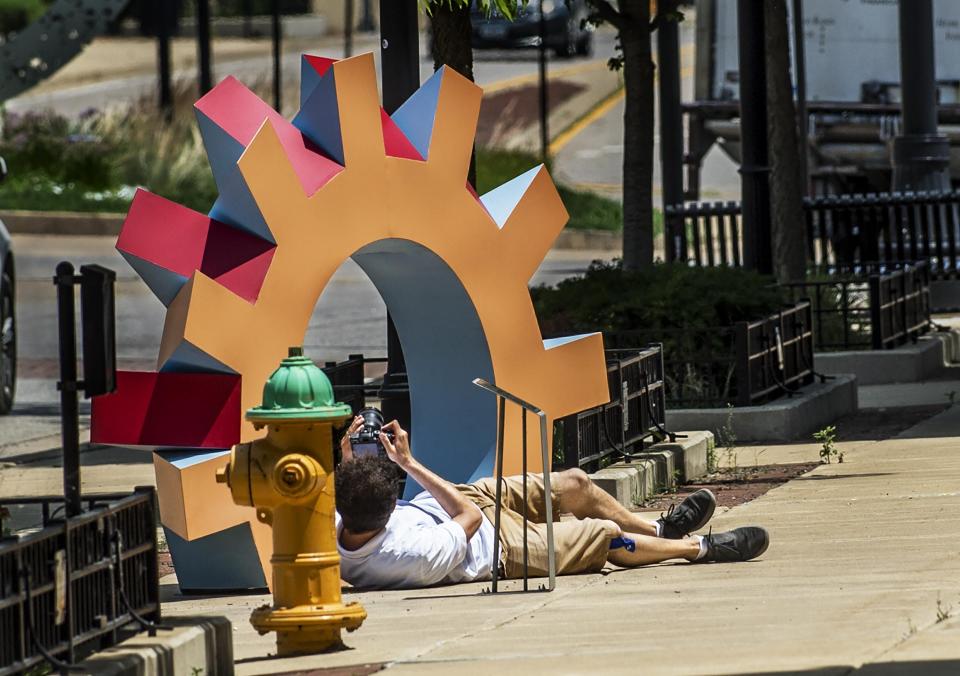 With final installation of the newest pieces complete, Videogenique owner Raphael Rodolfi goes low for an angle from which to work while producing a video Thursday, July 2, 2020, for ArtsPartners that will provide viewers with a virtual tour of Sculpture Walk along Washington Street in downtown Peoria.