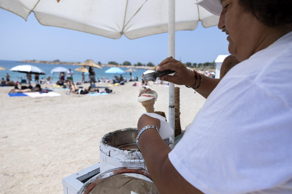 A vendor serves ice cream at Glyfada suburb, in Athens, Greece, Saturday, July 15, 2023. Temperatures reached up to 42 degrees Celsius in some parts of the country, amid a heat wave that continues to grip southern Europe. (AP Photo/Yorgos Karahalis)
