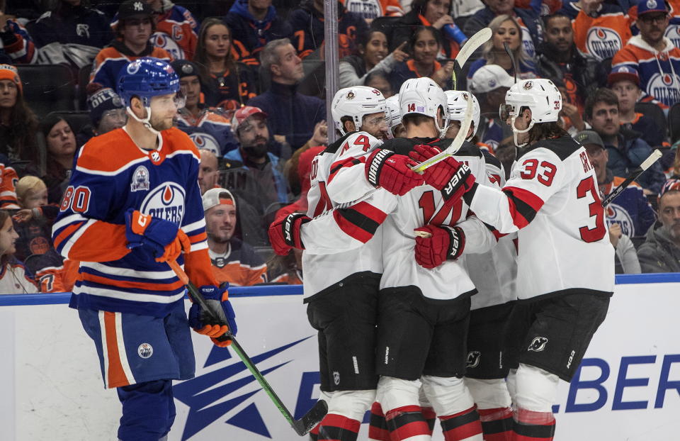 New Jersey Devils players celebrate a goal as Edmonton Oilers' Markus Niemelainen (80) skates past during the first period of an NHL hockey game Thursday, Nov. 3, 2022, in Edmonton, Alberta. (Jason Franson/The Canadian Press via AP)