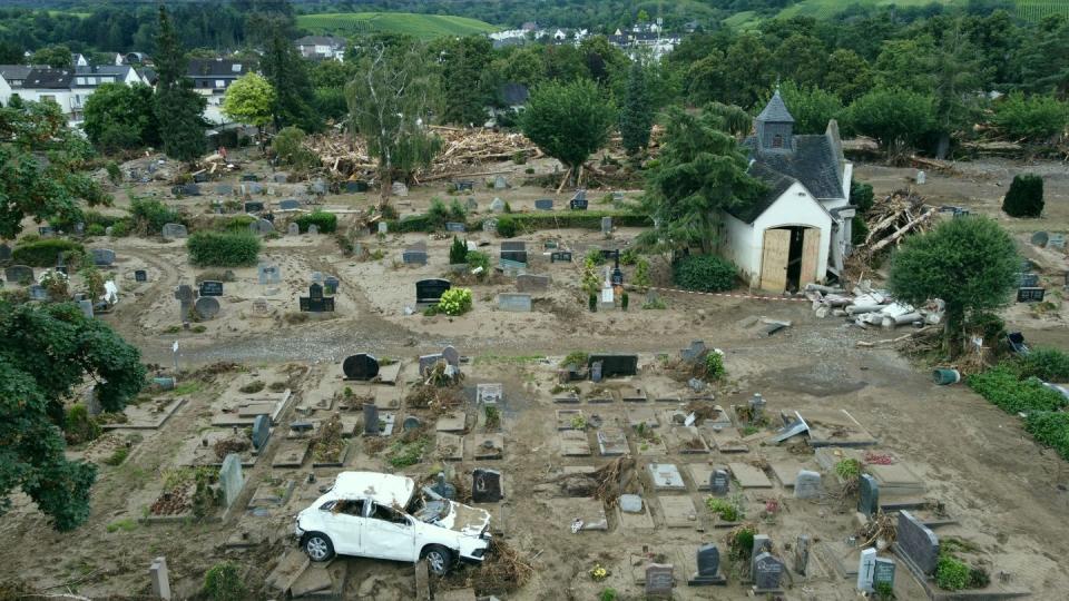 Ein Auto, das bei der Hochwasserkatastrophe auf den Friedhof geschwemmt worden ist, steht auf einem Grabfeld. Der Friedhof ist völlig zerstört. (Bild: dpa)