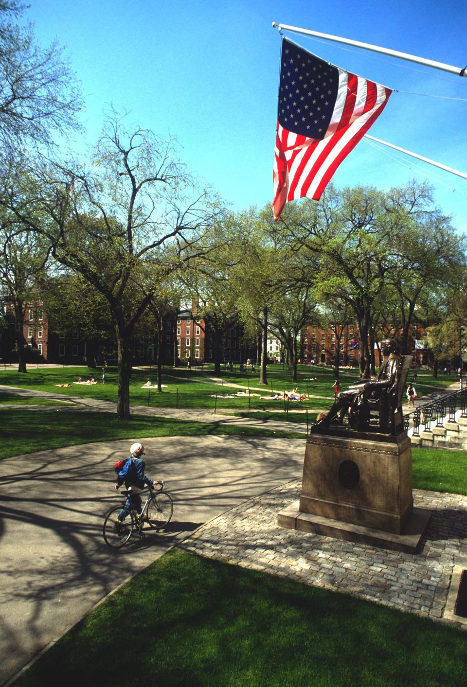 A photo of a student walking their bike on Harvard Yard.