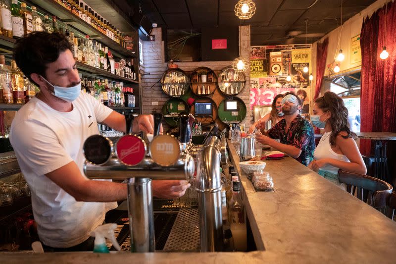 A bartender and customers wear face masks to fight the spread of the coronavirus disease (COVID-19) at a bar in Tel Aviv