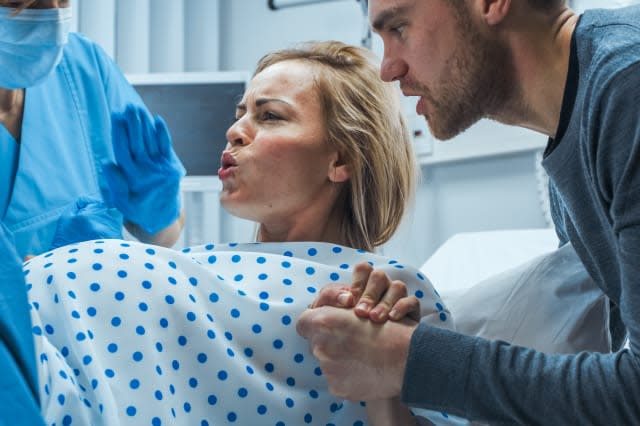 In the Hospital, Close-up on a Woman in Labor Pushing Hard to Give Birth, Obstetricians Assisting, Spouse Holds Her Hand. Modern Maternity Hospital with Professional Midwives.