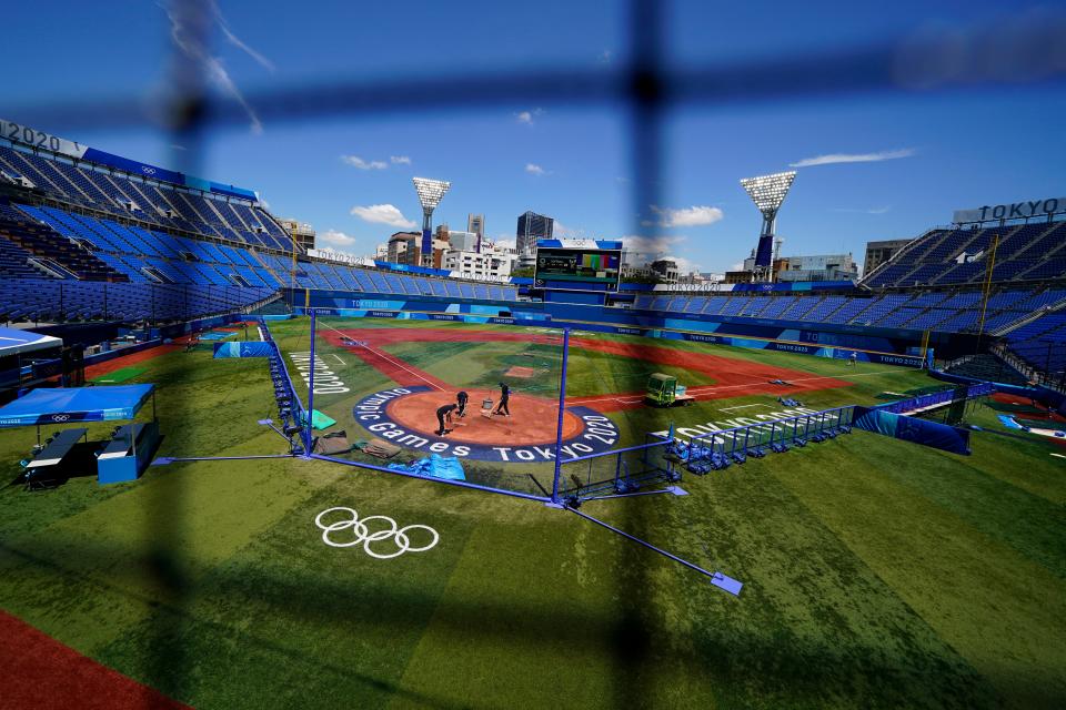 Workers prepare the field at Yokohama Baseball Stadium in preparation for softball competition at the 2020 Summer Olympics, Wednesday, July 21, 2021, in Yokohama, Japan.