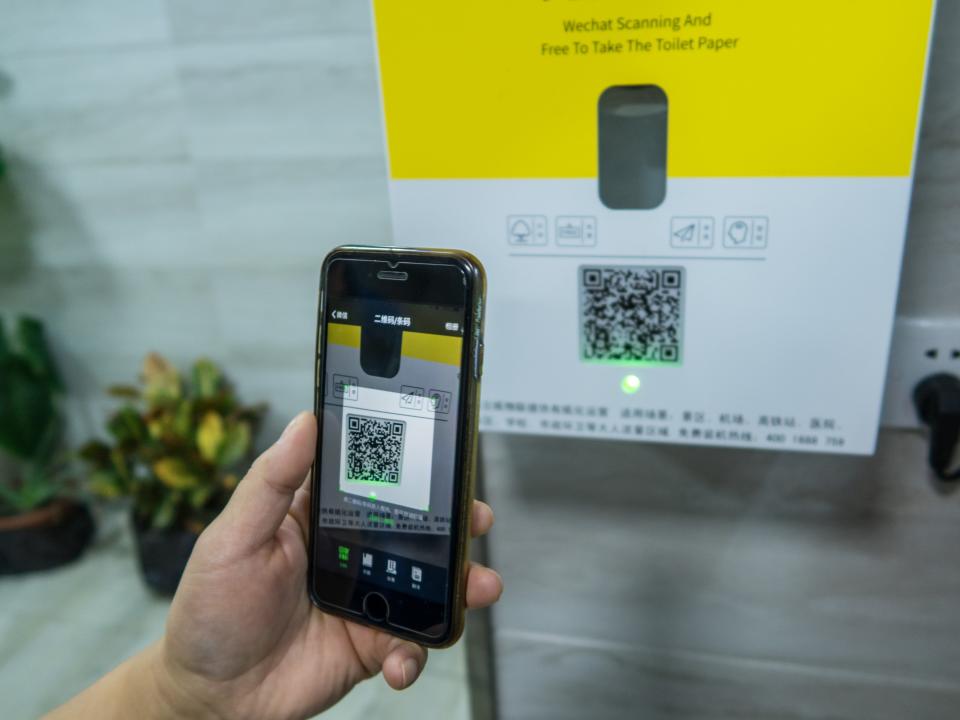 A citizen scans the QR code to get free toilet paper from an intelligent toilet paper issuing machine at a public toilet on October 9, 2018 in Shanghai, China. Citizens in Shanghai use mobile application Wechat to scan the QR code on an intelligent toilet paper issuing machine, which provides 80 centimeters long free toilet paper every time