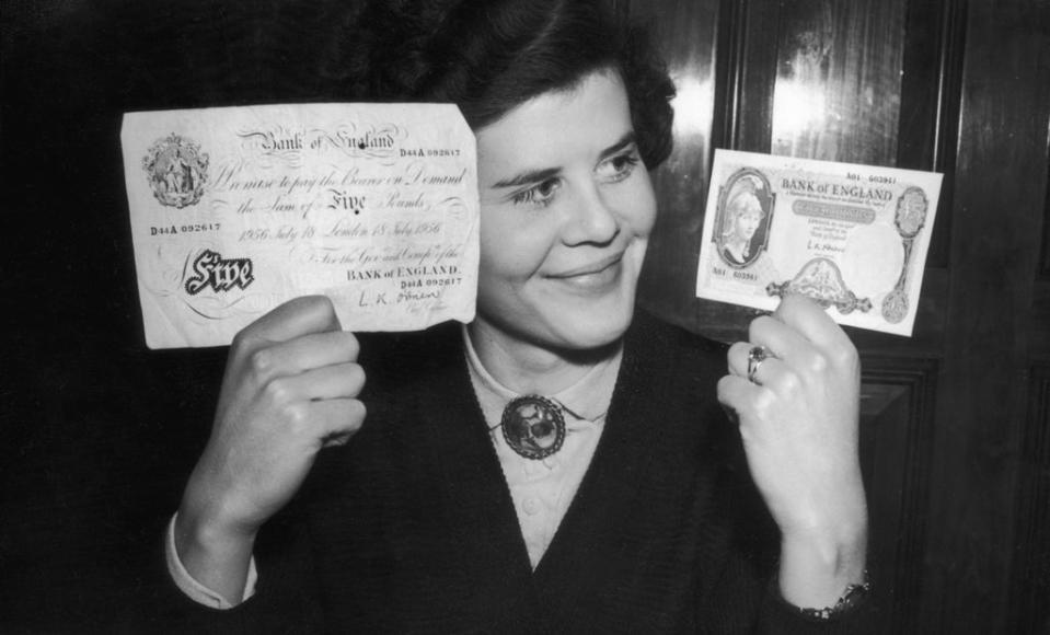 21 February 1957:  Deirdre Denbigh compares Britain’s old five pound note (left) with its smaller replacement on the day of its introduction (Getty)