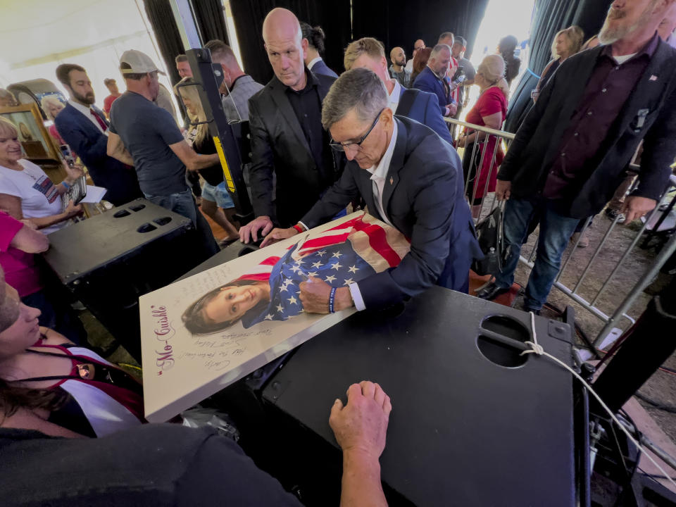 FILE - Michael Flynn, a retired three-star general who served as President Donald Trump's national security advisor, autographs a picture of a girl wrapped in an American flag during the ReAwaken America Tour at Cornerstone Church in Batavia, N.Y., Aug. 12, 2022. Flynn, one of the tour's founders and its star, warned the crowd that they were in the midst of a "spiritual war" and urges people to get involved in local politics." (AP Photo/Carolyn Kaster)