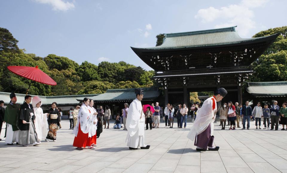 In this Saturday, May 4, 2013 photo, Shinto priests lead a Japanese couple under a parasol during a traditional wedding ceremony at Meiji Jingu Shrine in Tokyo. Meiji Jingu Shrine is a piece of old Tokyo not to be missed. Boasting the nation's largest wooden "torii" gate, the shrine was built more than 90 years ago to commemorate Emperor Meiji, who reigned as Japan opened to the rest of the world after centuries of isolation. (AP Photo/Koji Sasahara)