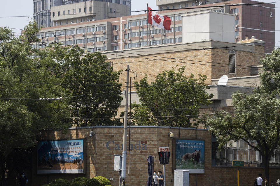 Residents pass by the Canadian Embassy in Beijing on Friday, June 19, 2020. Prosecutors charged two detained Canadians with spying Friday in an apparent bid to step up pressure on Canada to drop a U.S. extradition request for a Huawei executive under house arrest in Vancouver. (AP Photo/Ng Han Guan)