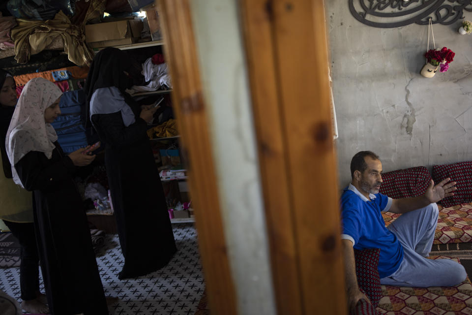 Maha Zorob and her daughter, left, scroll through old photos and videos of their destroyed home on their phones in Khan Younis, southern Gaza Strip, Monday, Aug. 28, 2023. The Gaza Strip's displaced families await the completion of nearly 1,400 Egyptian-sponsored housing units, a project mired in political disputes between the Palestinian Authority and Gaza's Hamas-run government. The Zorob family, like thousands of others, remains caught in the crossfire, living in makeshift conditions while nearly completed apartments stand empty.(AP Photo/Fatima Shbair)