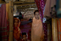 Relatives of Rohingya refugees Sitara Begum, not in picture, whose names are in the list to be repatriated, watch her speak with the Associated Press inside her shelter at Jamtoli refugee camp, near Cox's Bazar, Bangladesh, Thursday, Nov. 15, 2018. The head of Bangladesh's refugee commission said plans to begin a voluntary repatriation of Rohingya Muslim refugees to their native Myanmar on Thursday were scrapped after officials were unable to find anyone who wanted to return. (AP Photo/Dar Yasin)