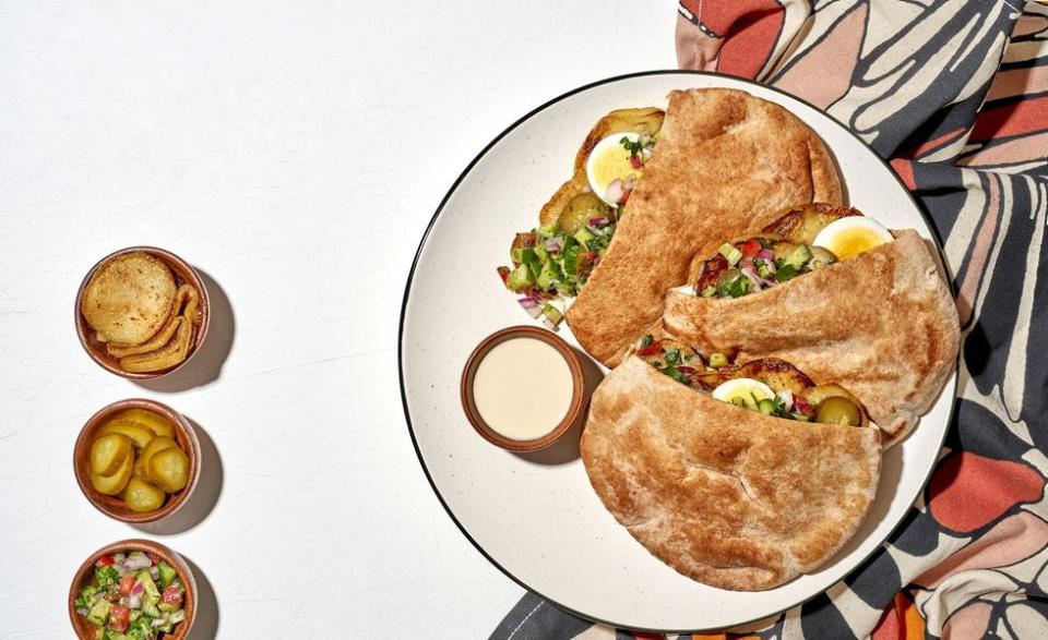 eggplant slices, fresh cucumber salad, and creamy tahini sauce in a sabich sandwich