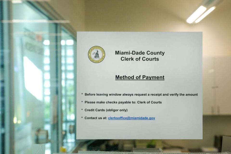 Un cartel con información sobre cómo pagar las tasas judiciales pegado a una ventana de cristal en la oficina del secretario del tribunal del Condado Miami-Dade, dentro del edificio de tribunales de menores en el downtown de Miami, el lunes 13 de febrero de 2023.