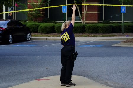 An FBI agent holds up crime scene tape as federal agents execute search warrants on multiple businesses in Lawrenceville