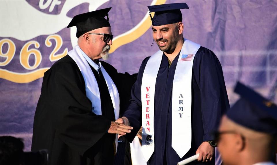 Merced College graduate Jose Ramirez Enrquez, right, receives his diploma from Merced College Board of Trustees President John Pedrozo during the school’s 60th commencement ceremony on Friday, May 26, 2023.