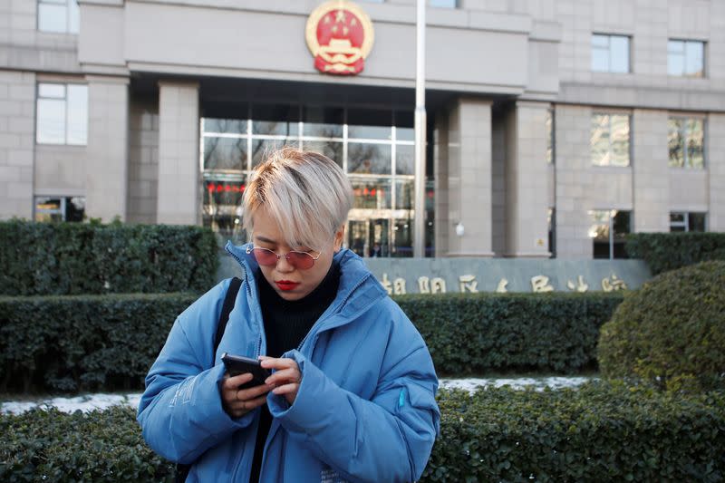 Teresa Xu checks her phone outside Chaoyang People's Court before a court hearing in Beijing