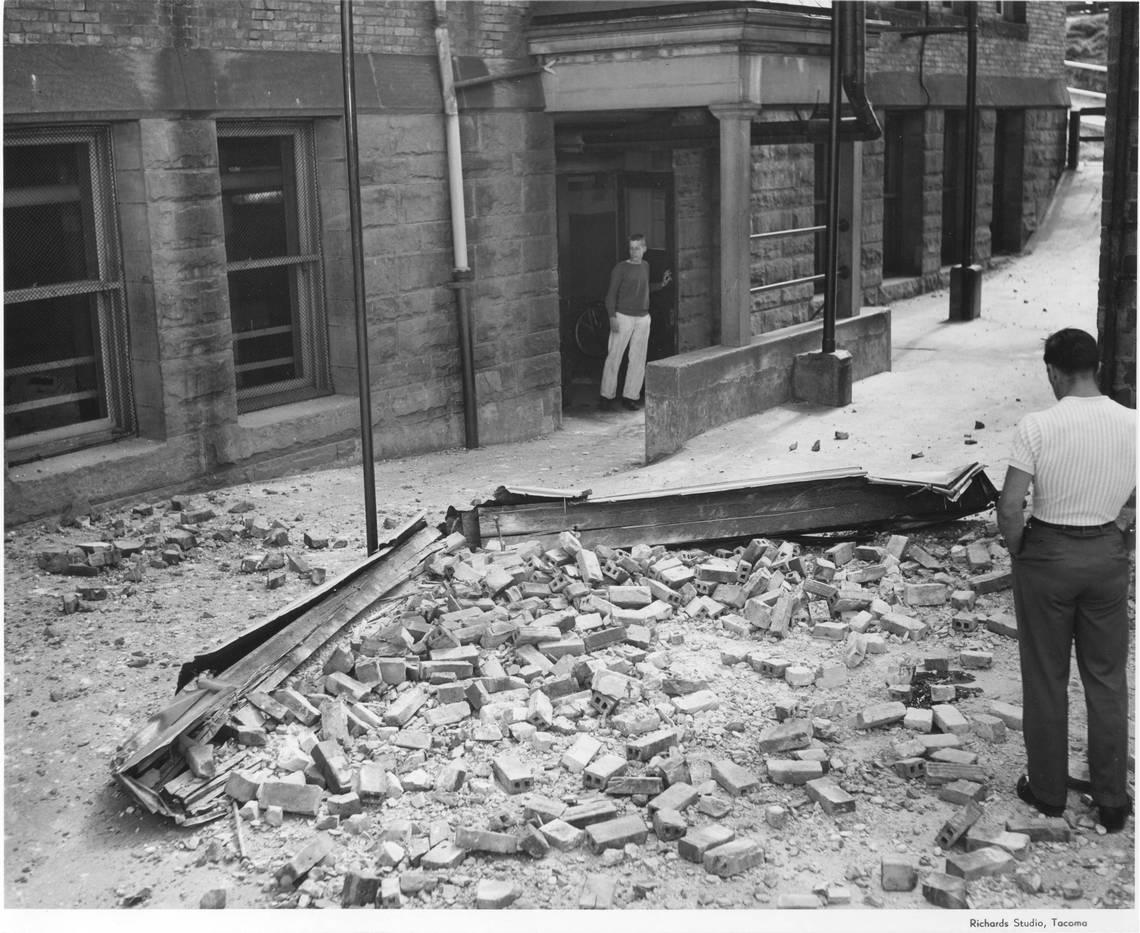 On April 13, 1949, at 11:55 am, Tacoma was hit by a magnitude 7.1 earthquake. Bob Anderle (far right) looks down at the broken gable and the facing bricks that fell from one of the dormer windows at Lowell School during the quake killing eleven-year-old Marvin Klegman. In all, eight people in Washington died as a direct result of the earthquake.