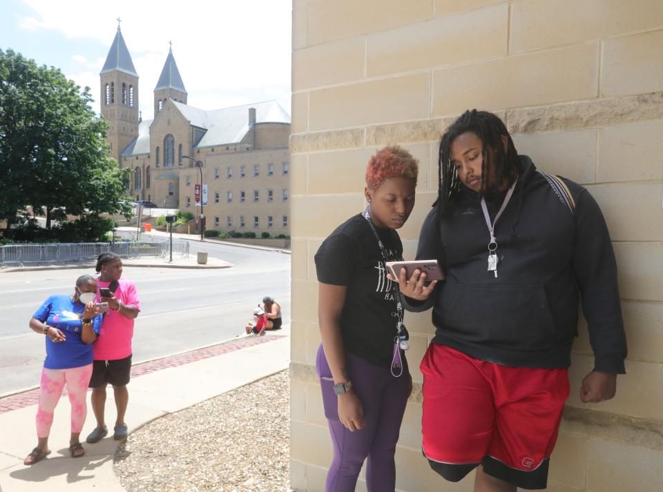 People stand in front of the Stubbs Justice Center on Sunday watching footage of Jayland Walker's shooting by Akron police.