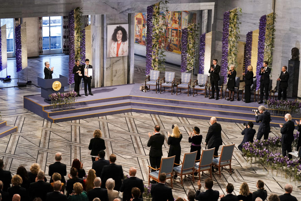 Ali and Kiana Rahmani receive the Nobel Peace Prize for 2023 for their mother, imprisoned Iranian activist Narges Mohammadi, shown on the screen, in Oslo City Hall, Oslo, Norway, Sunday, Dec. 10, 2023. Mohammadi is renowned for campaigning for women's rights and democracy in her country, as well as fighting against the death penalty. (Fredrik Varfjell/NTB via AP)