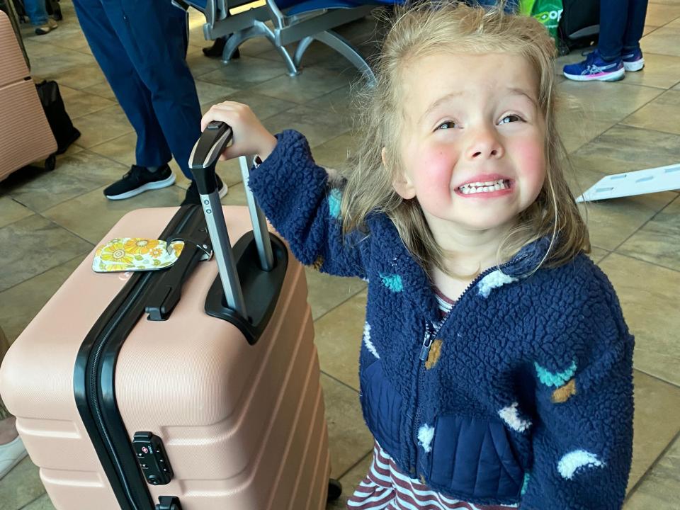 lauren's daughter standing next to a suitcase and posing for a photo in a train station