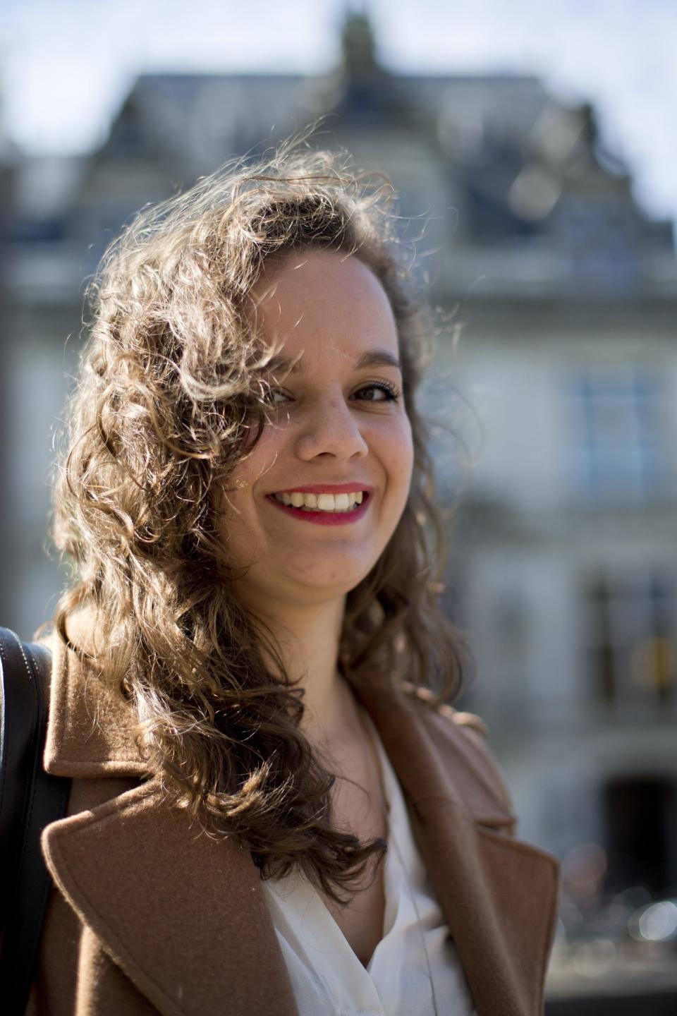 In this Wednesday April 16, 2014 photo, Charlotte van den Berg poses for a portrait outside the NIOD Institute for War, Holocaust and Genocide Studies, rear, in Amsterdam, Netherlands. Charlotte van den Berg was a 20-year-old college student working part-time in Amsterdam’s city archives when she and other interns came across a shocking find: letters from Jewish Holocaust survivors complaining that the city was forcing them to pay back taxes and late payment fines on property seized after they were deported to Nazi death camps. Van den Berg waged a lonely fight against Amsterdam’s modern bureaucracy to have the travesty publicly recognized. Now, largely due to her efforts, Amsterdam officials are considering compensating Holocaust survivors for the taxes and possibly other obligations, including gas bills, they were forced to pay for homes that were occupied by Nazis or collaborators while the rightful owners were in hiding or awaiting death in the camps. (AP Photo/Peter Dejong)