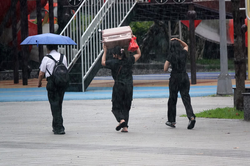 北北基高屏大雨特報（1） 中央氣象署16日下午發布大雨特報，對流雲系發展旺 盛，易有短延時強降雨，大台北、南投地區及西半部 山區有局部大雨發生機會。圖為台北南港車站民眾舉 起行李箱擋雨。 中央社記者鄭傑文攝  113年6月16日 