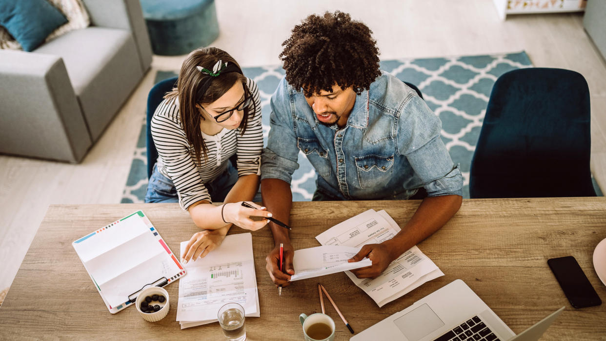 Modern married multi-ethnic young couple calculating financial bills at home.