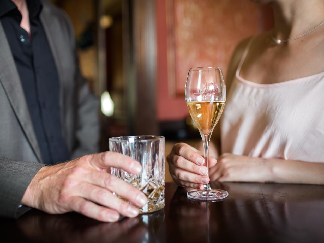 A stock image of a man and woman holding drinks at a bar.