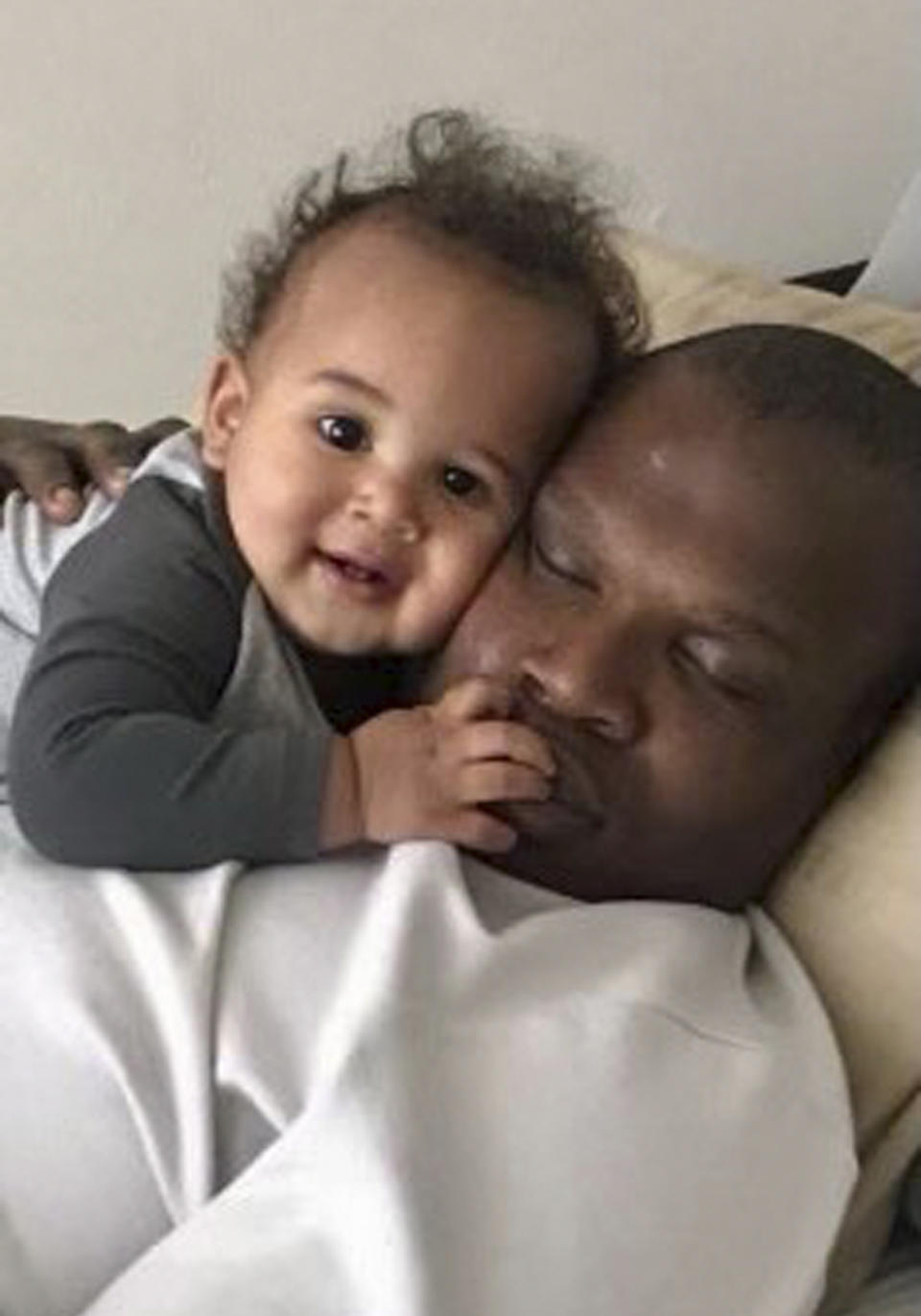 In this undated photo provided by Lindsay Myeni, Lindani Myeni holds his infant son, Nsizwa, as he sleeps. Myeni was fatally shot by Honolulu police in 2021 after he physically attacked officers, who responded when an upset occupant of a home complained a stranger had entered uninvited wearing a feathered headband and made bizarre comments. Results of studies of Myeni's brain tissue, obtained by The Associated Press, show the 29-year-old South African rugby player had Stage 3 CTE, or brain trauma caused by repeated concussions. (Lindsay Myeni via AP)