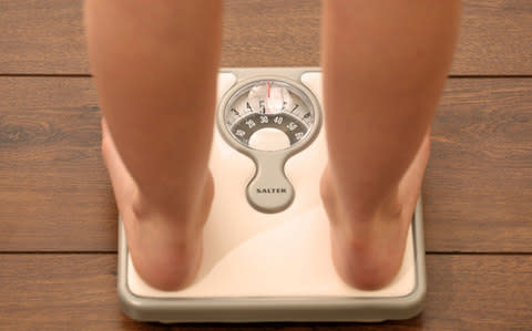 Child using a set of weighing scales - Credit: PA