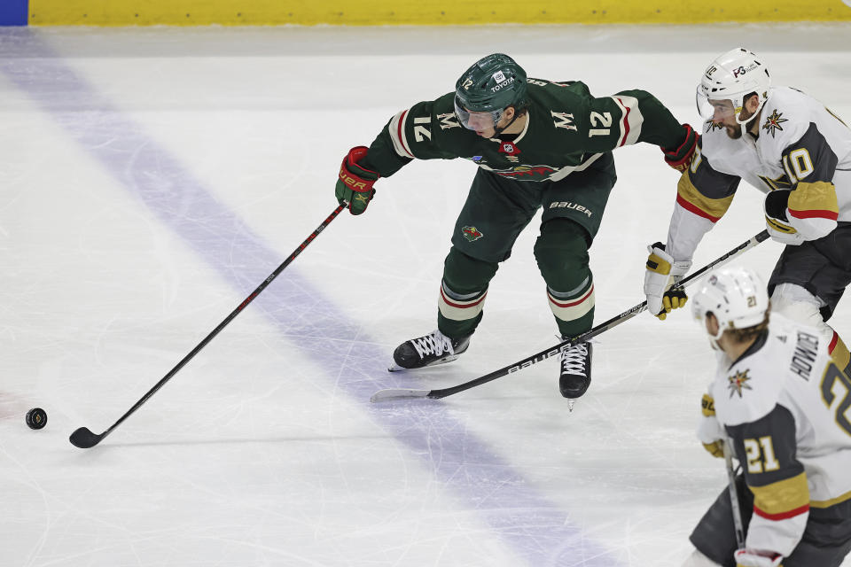 Minnesota Wild left wing Matt Boldy (12) goes after the puck against Vegas Golden Knights center Nicolas Roy (10) during the first period of an NHL hockey game Monday, April 3, 2023, in St. Paul, Minn. (AP Photo/Stacy Bengs)