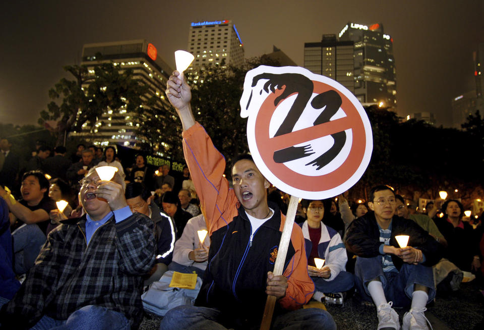 FILE - Holding a sign of anti-Article 23 bill, pro-democracy activists shout slogans during a candlelight vigil at a downtown Hong Kong park on Feb. 25, 2003. Hong Kong’s plan to enact a new national security law, on top of a sweeping legislation that was imposed by Beijing and used to crack down on dissent, is deepening concerns over the erosion of freedoms in the former British colony.(AP Photo/Vincent Yu, File)