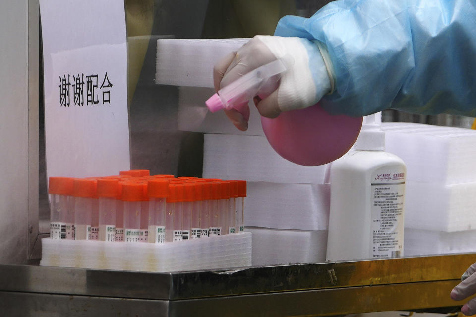 A medical worker sprays disinfectant on COVID-19 test samples collected from people at a mobile coronavirus testing facility a residential area in Beijing, Wednesday, Jan. 19, 2022. With just over two weeks before the opening of the Beijing Winter Olympics, residents of the Chinese capital say they’re disappointed at not being able to attend events because of coronavirus restrictions that have seen parts of the city placed under lockdown. (AP Photo/Andy Wong)