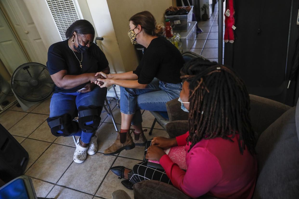 Workers visit woman in her home.