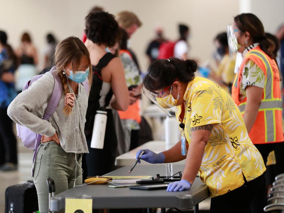 A traveler is assisted by a state official at the Daniel K. Inouye International Airport Thursday, Oct. 15, 2020, in Honolulu.
