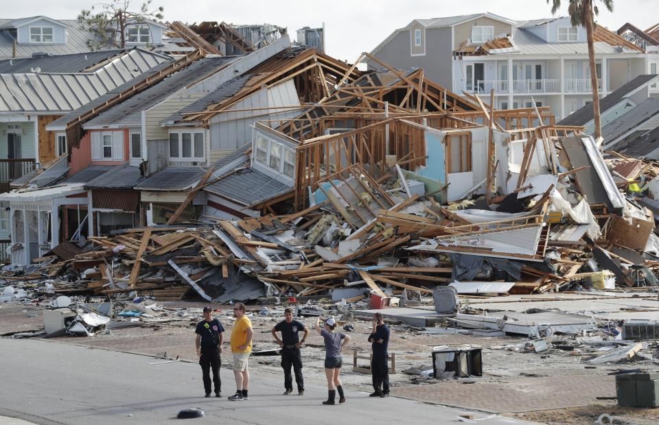 FILE- In this Oct. 11, 2018 file photo, rescue personnel perform a search in the aftermath of Hurricane Michael in Mexico Beach, Fla. A year after Hurricane Michael, Bay County, Florida, is still in crisis. Thousands are homeless, medical care and housing are at a premium, and domestic violence is increasing. Michael was among the strongest hurricanes ever to make landfall in the United States. This summer, county officials unveiled a blueprint to rebuild. Among their ideas: Use shipping containers and 3-D technology to build new houses and offer signing bonuses to lure new doctors. (AP Photo/Gerald Herbert, File)