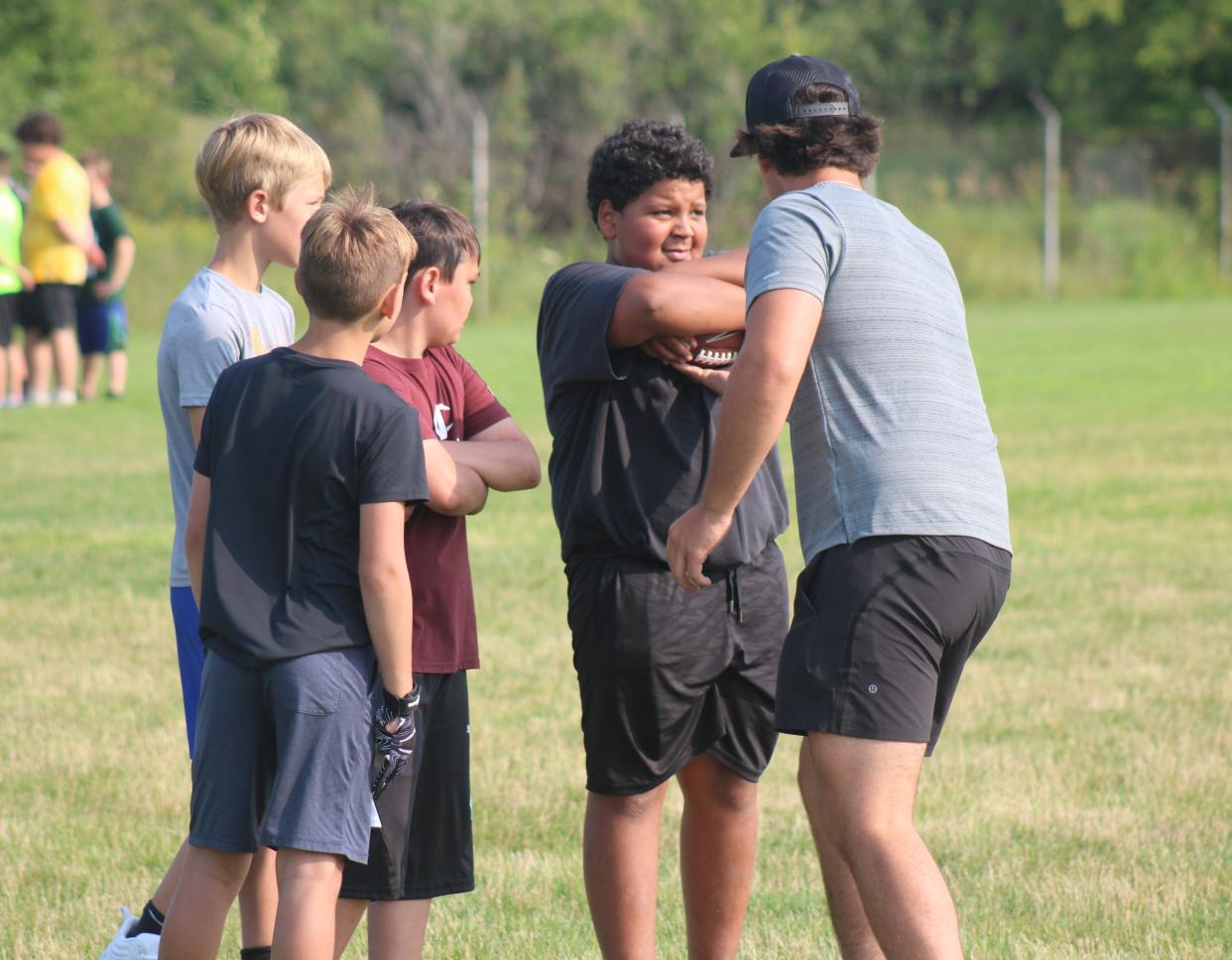 Campers listen to Cheboygan junior football player Sean Postula during Day 1 of the Cheboygan youth football camp at Western Avenue Field on Monday.